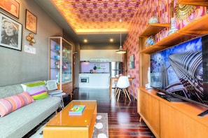 Una sala de estar moderna con un sofá, una mesa de centro y un televisor sobre un mueble de madera.