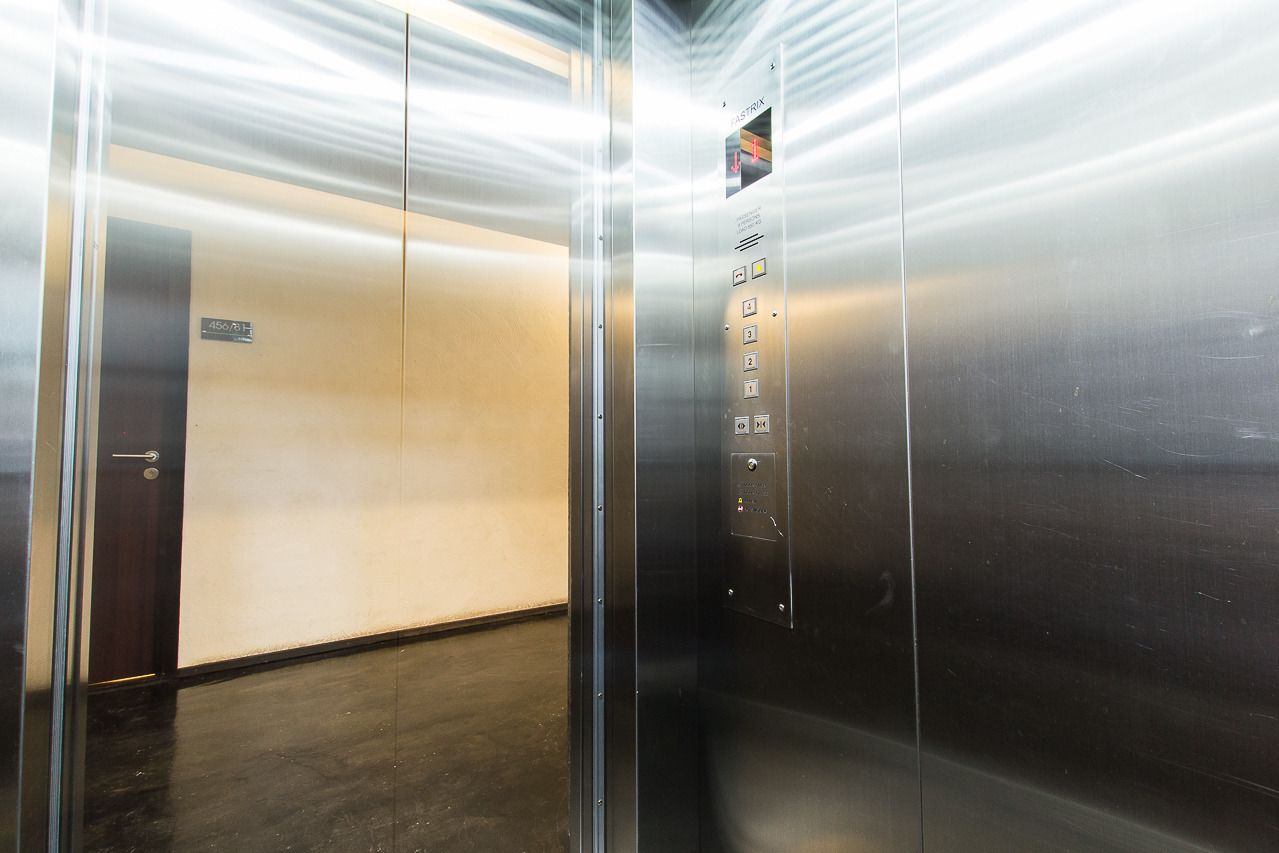 Un ascensore con interni metallici, una porta con maniglia e un pannello di controllo con pulsanti.