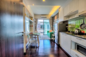Una cocina moderna con comedor, un sofá verde y vistas a través de un ventanal.