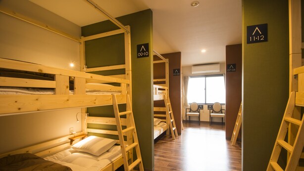 Un dormitorio con literas, escaleras de madera y carteles con los números de las habitaciones.