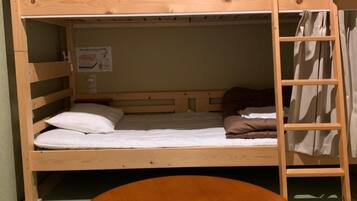 Una cama litera con escalera de madera y una mesa al frente.