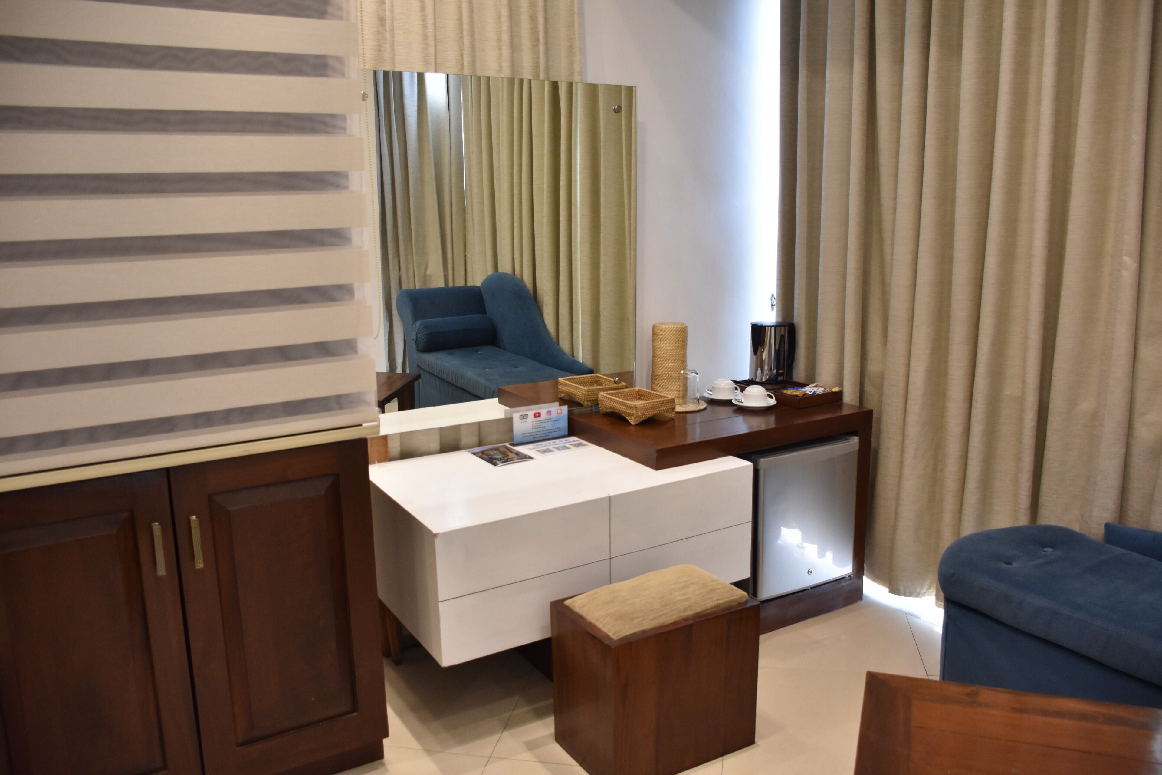 A modern living area with a sofa, a coffee table, a small wooden bench, a white cabinet, and a mirror.