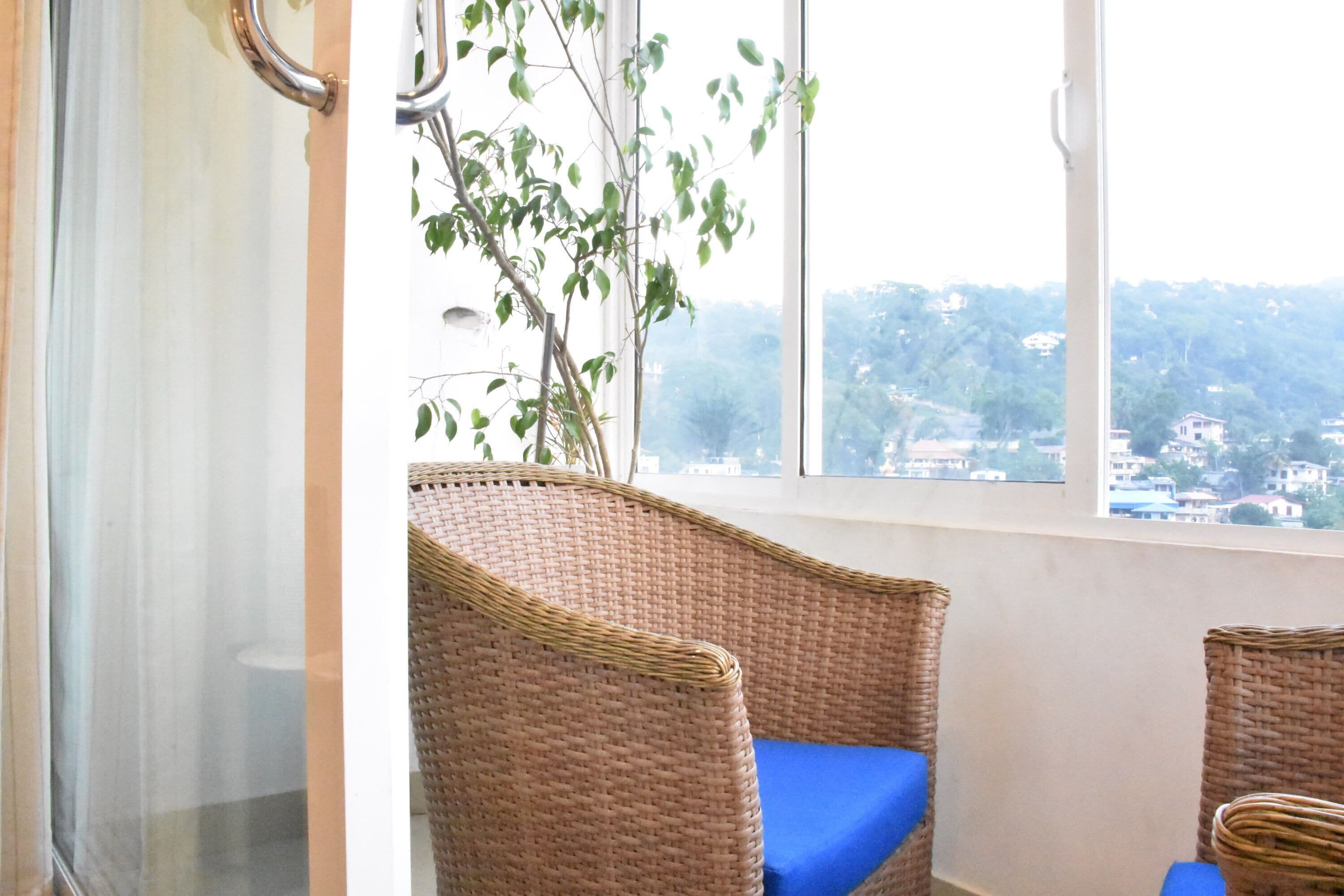 A room with wicker chairs and a view of a hillside.