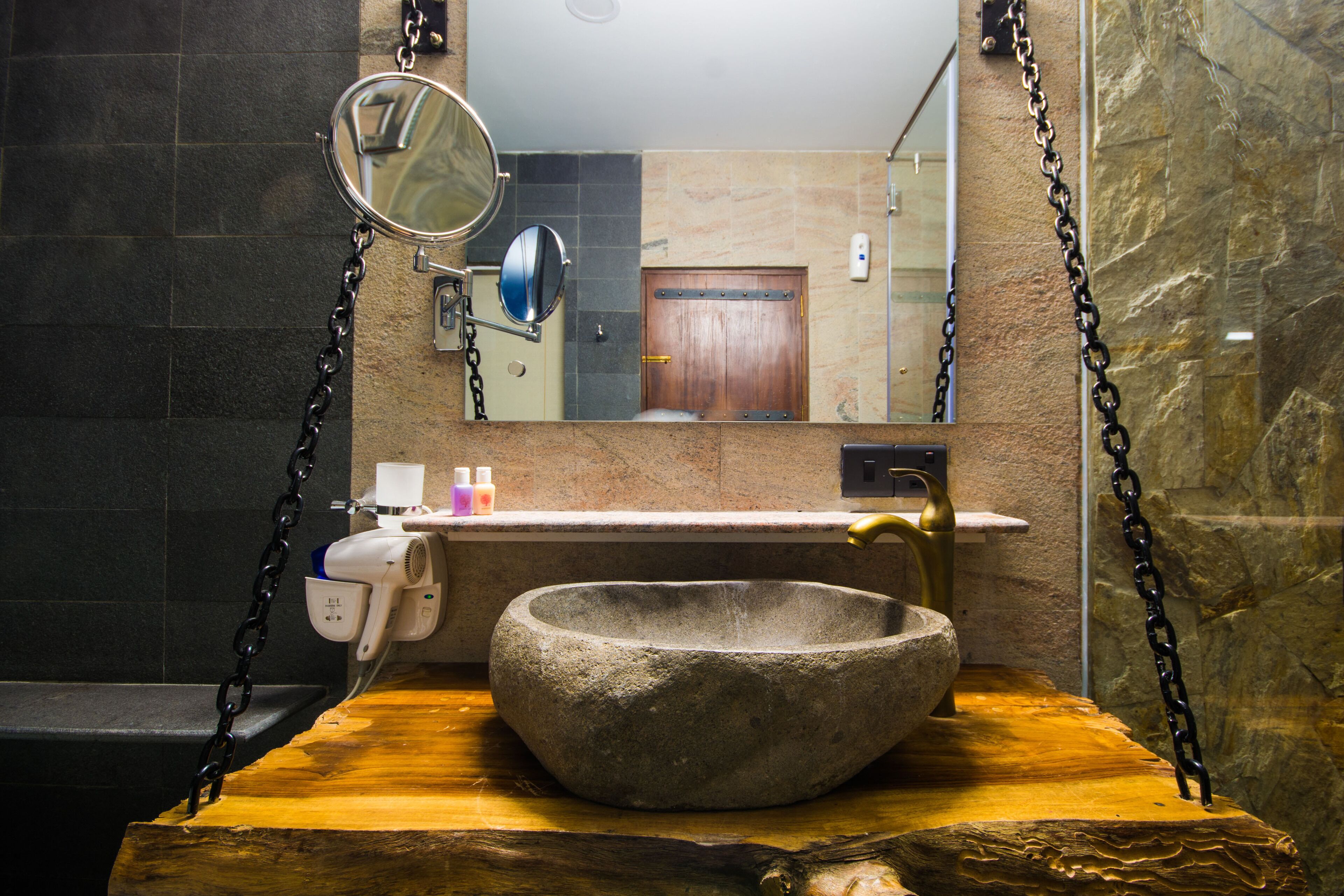 Un baño con lavamanos de piedra, un espejo y zona de ducha.