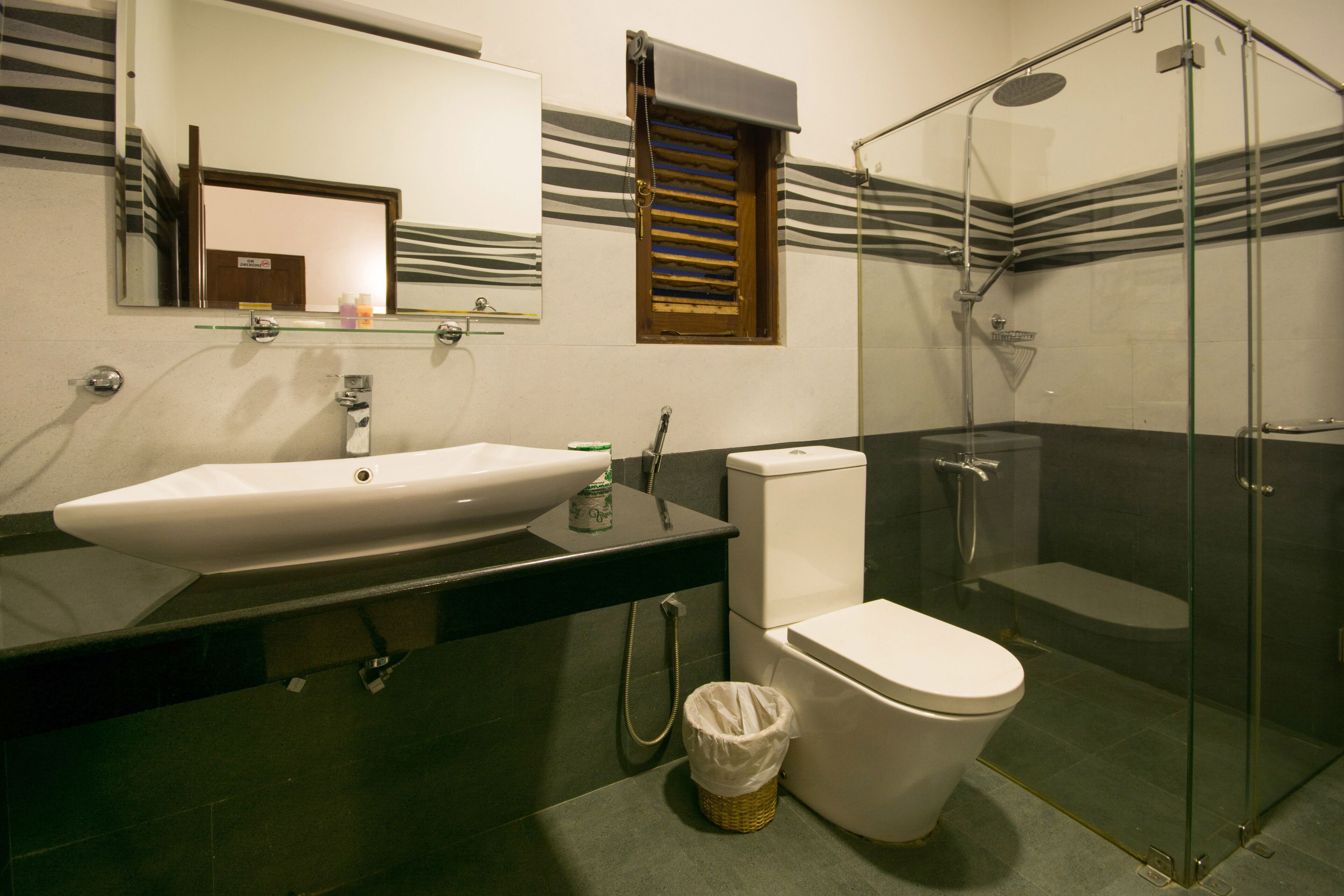 Un bagno moderno con cabina doccia in vetro, lavandino bianco e water.