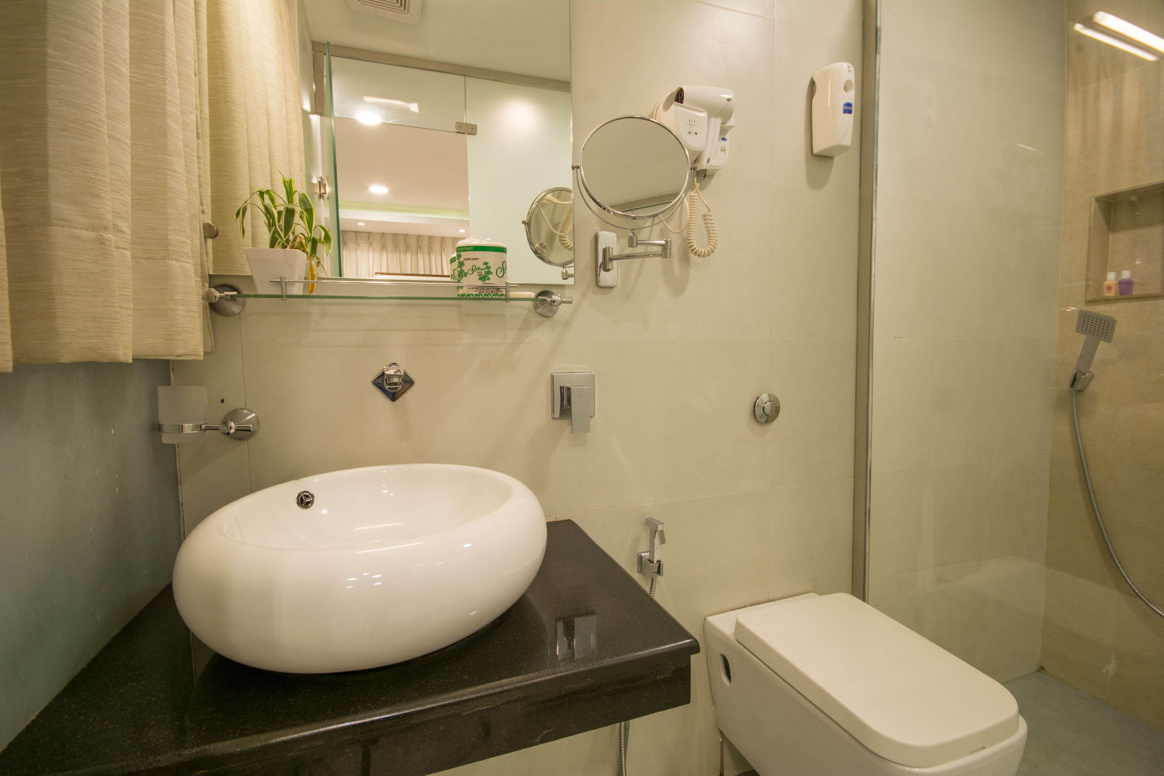 Een badkamer met een wit wastafel, een spiegel, een toilet en een douche.