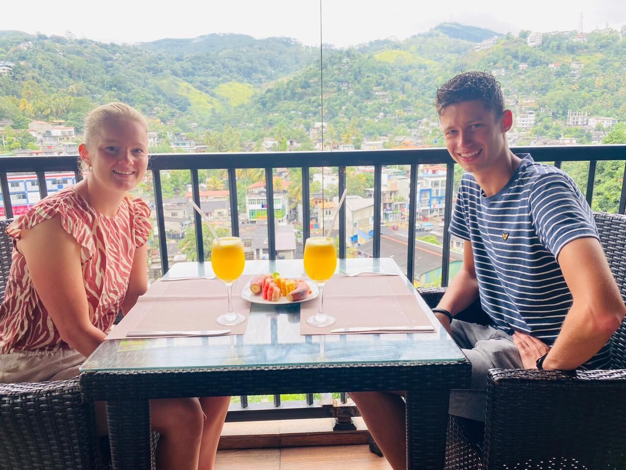 Two people seated at a table with a view of a hillside.