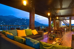 An outdoor seating area with a sofa and chairs, a dining table, and a staircase leading to an upper level. - Kandy City Stay (Kandy)