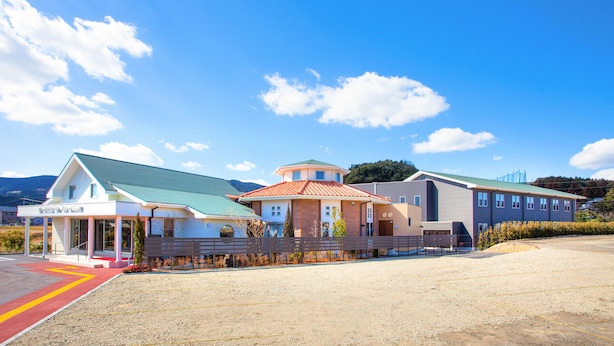 A hotel with a red-roofed building, a blue-roofed building, and a white building with a green roof.
