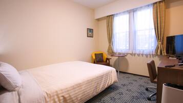 Een hotelkamer met een bed, een bureau, een stoel, een televisie en een kleine tafel.