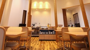 A high-ceilinged dining area with wooden beams, a central kitchen, and multiple seating arrangements.