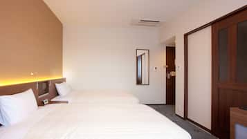 A hotel room with two beds, a wooden wardrobe, a mirror, and a bedside table.