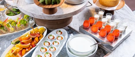 Un bufé con diversos alimentos, incluyendo frutas, ensaladas y postres.