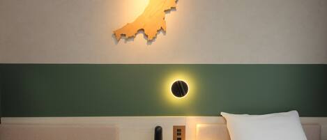 Una habitación de hotel con un adorno de madera en la pared, una lámpara de noche, un teléfono y una cama con ropa blanca.