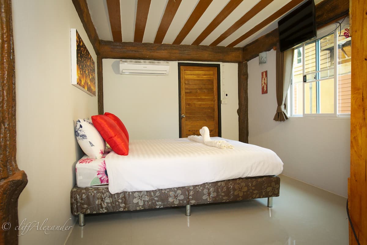 Een slaapkamer met een bed, een houten deur en een raam met gordijnen.