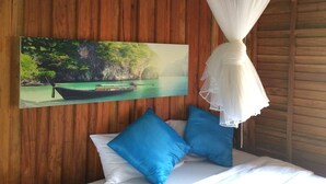 A bedroom with a bed, blue pillows, a white canopy, and a painting of a boat on water. - The Ford Sunset Beach Resort (Ko Pha-ngan)