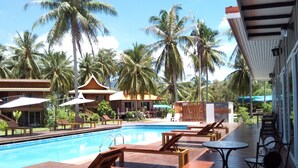 A poolside area with wooden loungers, a small table, and a covered seating area. - The Ford Sunset Beach Resort (Ko Pha-ngan)