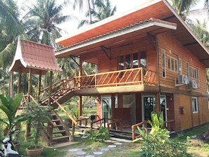 A wooden house with a balcony, a staircase, and a small garden area. - The Ford Sunset Beach Resort (Ko Pha-ngan)
