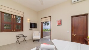 A bedroom with a bed, a chair, a television, and a door leading to a balcony. - Mount Havana (Udapalatha)