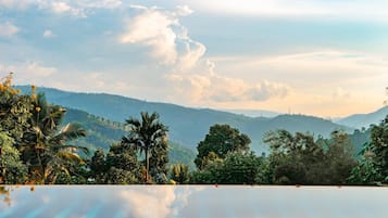 Relax by the serene pool overlooking lush greenery and distant hills.