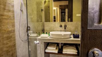 A modern bathroom with a glass-enclosed shower, a sink with a mirror above it, and a wooden door.