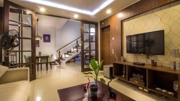 A modern living room with a sofa, coffee table, TV, and a staircase leading to another level.