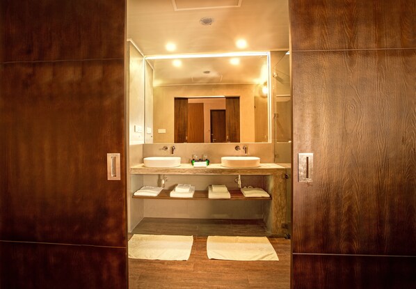 Un baño con dos lavamanos, un espejo y toallas en el suelo.