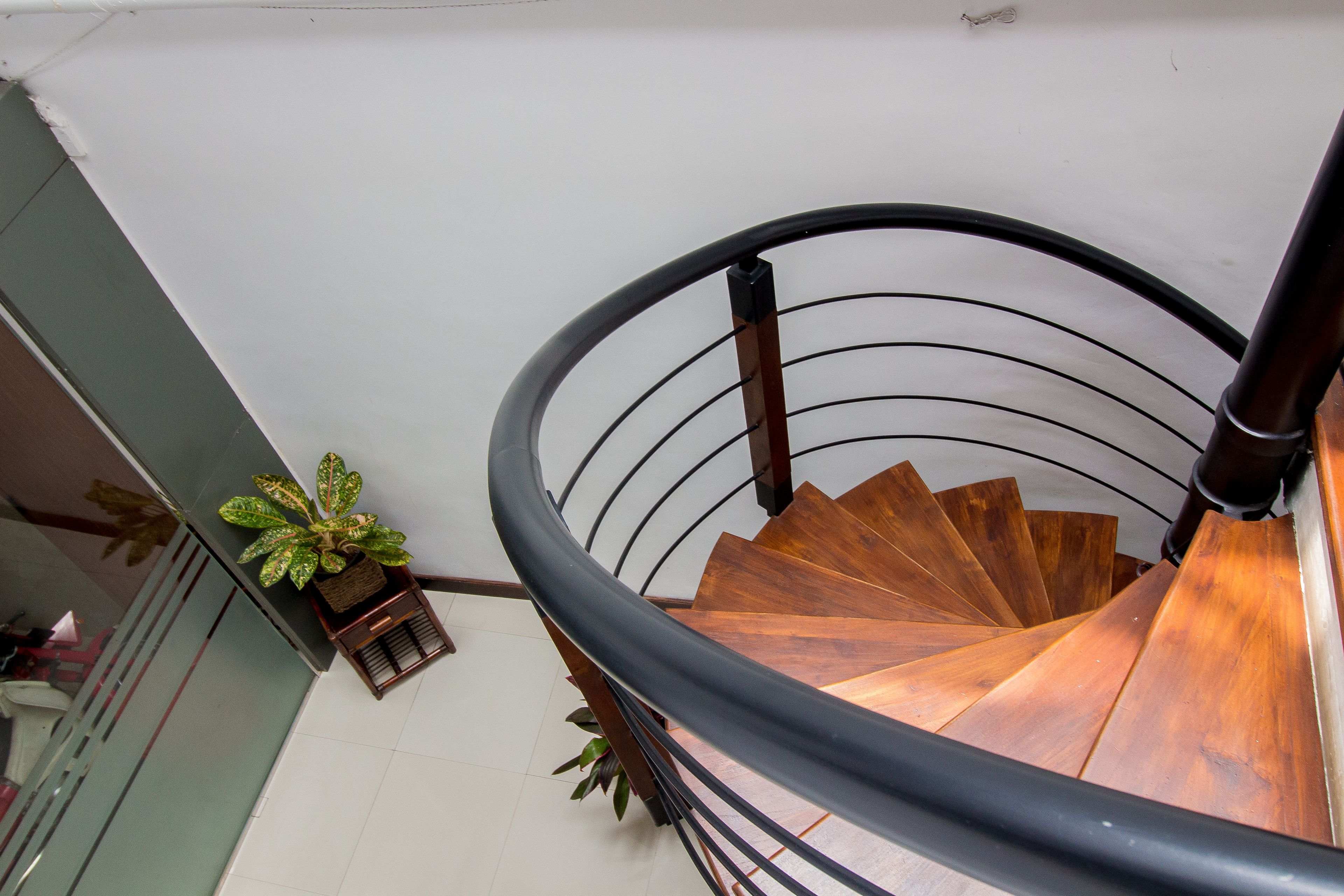 Una escalera de caracol con escalones de madera y barandilla de metal negro.