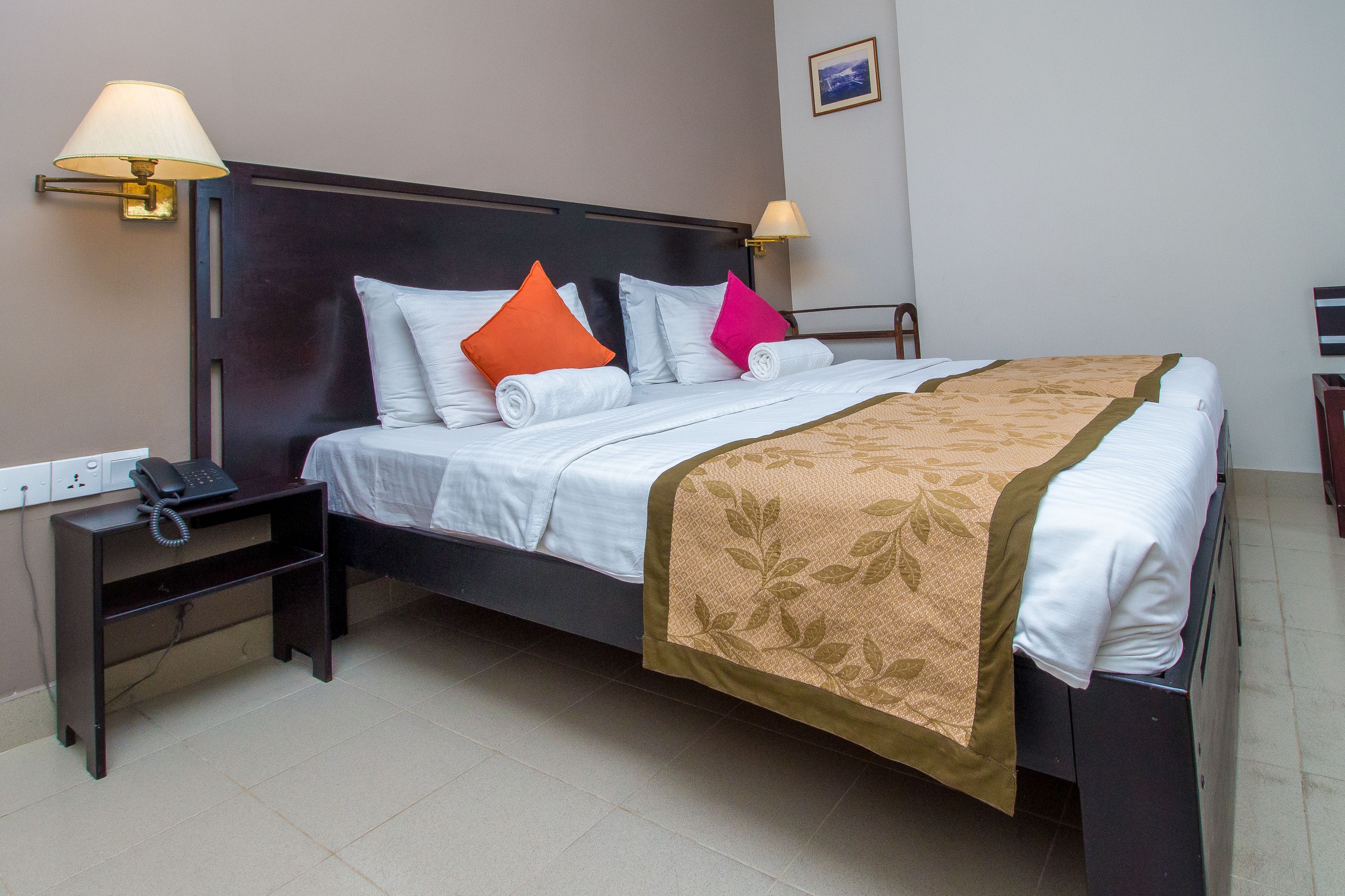 A neatly made bed with a headboard, a bedside table with a lamp, and a phone.