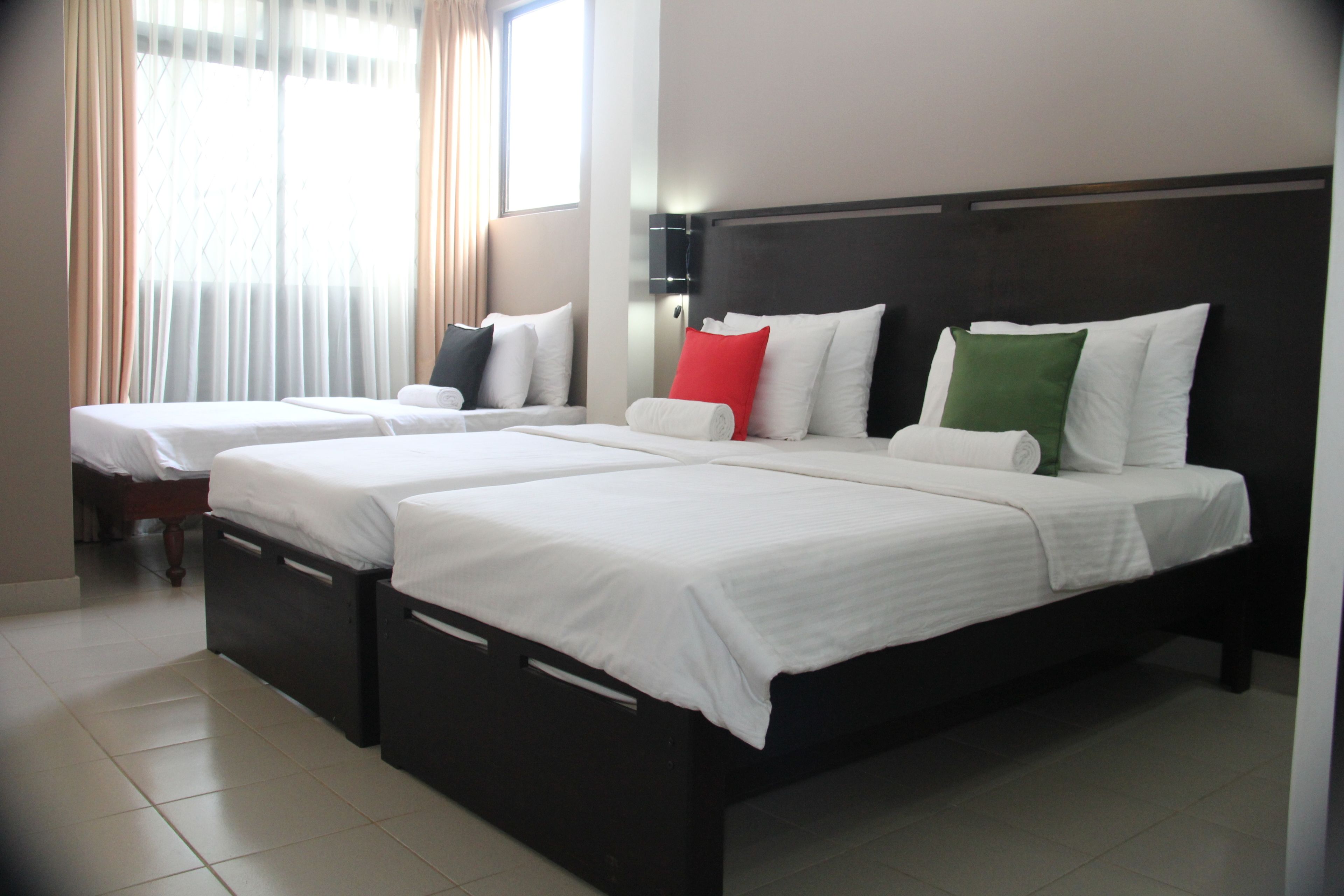 A hotel room with two beds, each with white bedding and pillows in various colors.