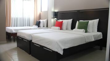 A hotel room with two beds, each with white bedding and pillows in various colors.