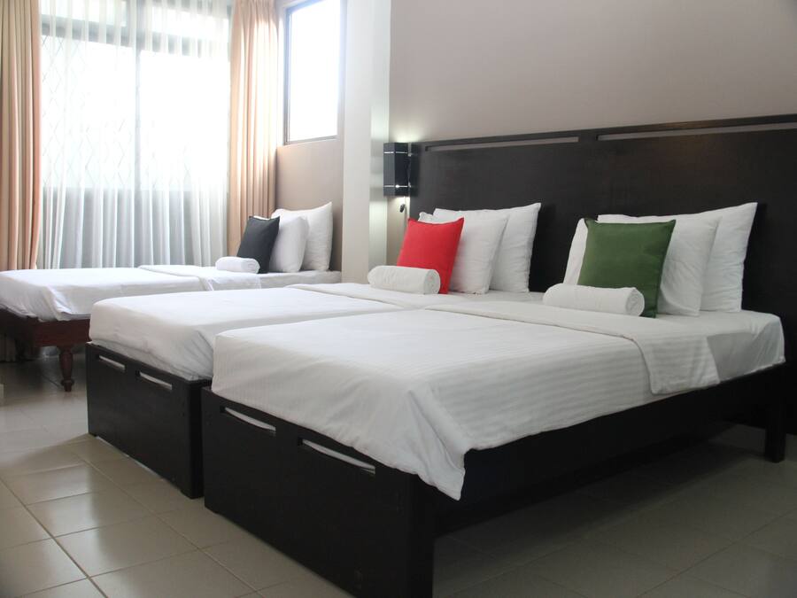 A hotel room with two beds, each with white bedding and pillows in various colors.