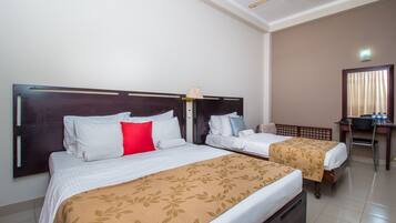 A hotel room with two beds, a desk, and a ceiling fan.