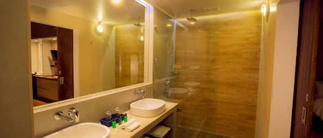 A modern bathroom with two sinks, a large mirror, and a glass-enclosed shower area.