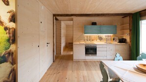 A wooden interior with a kitchen area, including a stove, cabinets, and a dining table.