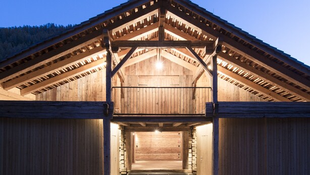 A large, open wooden barn with a high ceiling and a sloped roof.