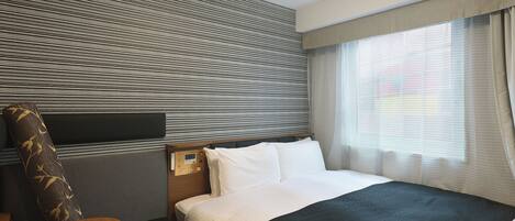 A hotel room with a bed, bedside table, and a headboard with a control panel.