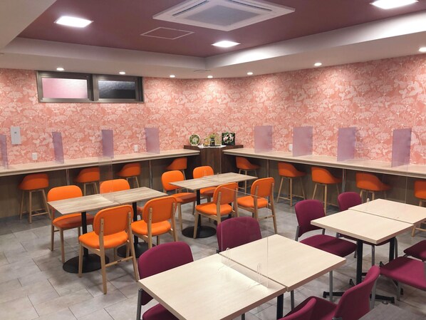 Uma sala de conferências com mesas e cadeiras, papel de parede floral e luminárias no teto.