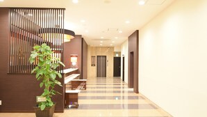 A hotel lobby with a checkered floor, a potted plant, a staircase, and a reception desk. - APA Hotel Kagoshima Tenmonkan (Kagoshima)