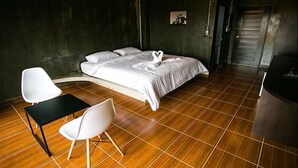 Une chambre d’hôtel moderne avec un grand lit, des chaises blanches et un plancher en bois.