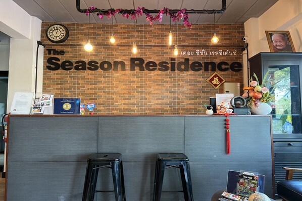 A reception area with a brick wall, a clock, and a sign reading "The Season Residence".