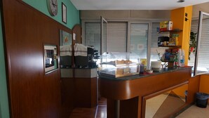 A kitchen with a wooden counter, a coffee machine, and a window with blinds. - Hotel San Marco (Pesaro)