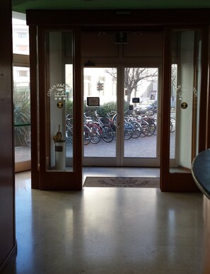 A hotel entrance with a glass door leading to a parking area with bicycles. - Hotel San Marco (Pesaro)