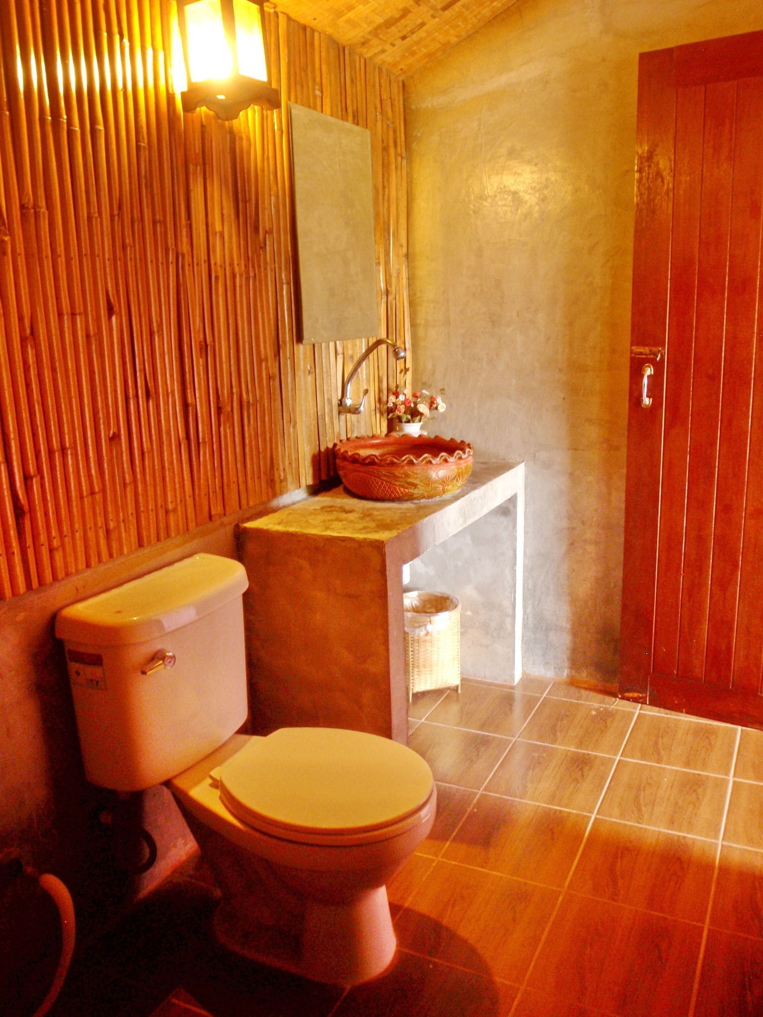 A bathroom with a toilet, sink, and wooden wall paneling.