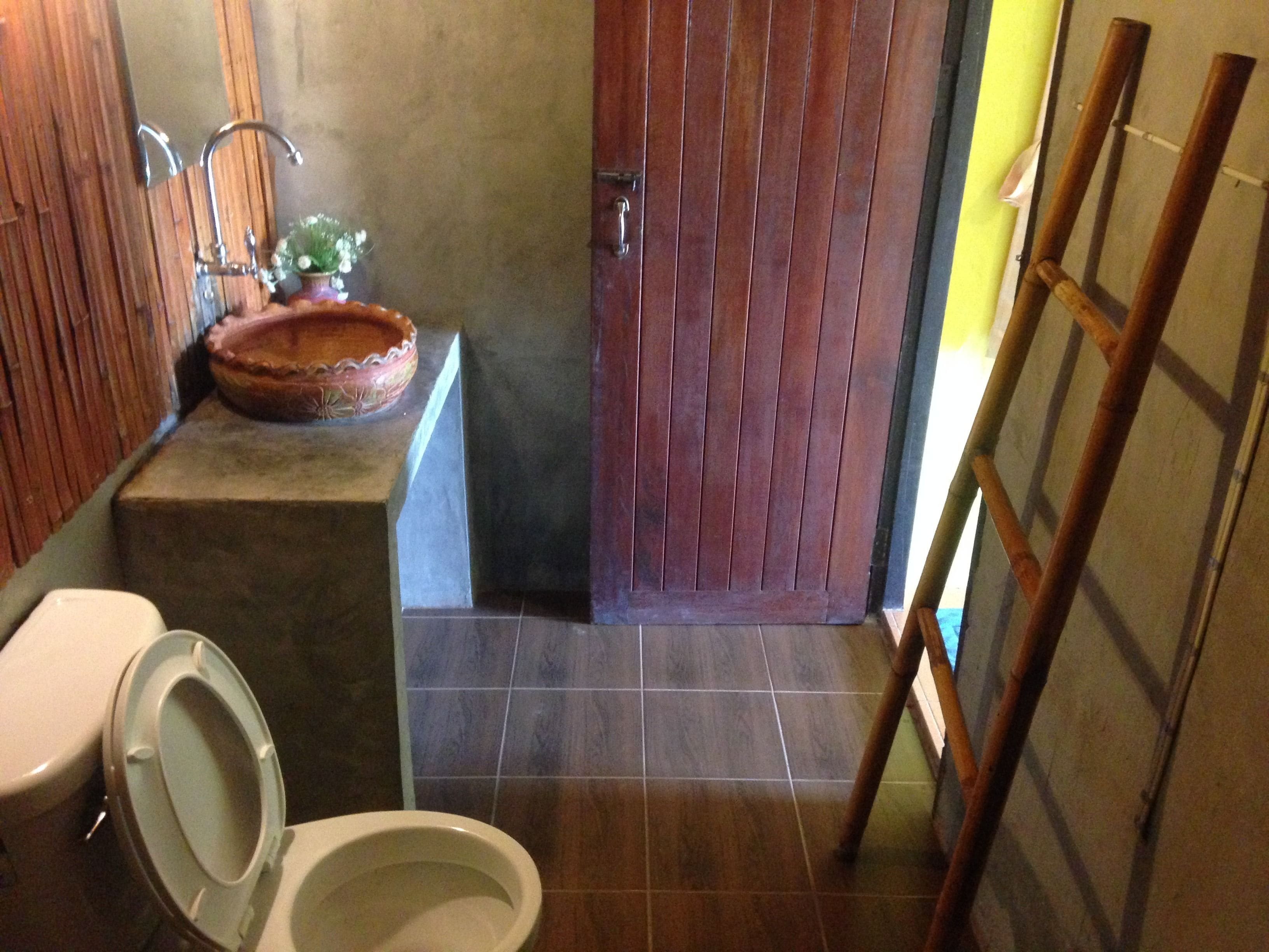 Ein Badezimmer mit Toilette, Waschbecken und Holztür.