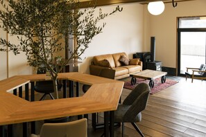 Un salon moderne avec une table à manger en bois, un canapé en cuir et une grande plante.