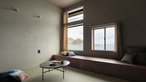 Een kamer met een inbouwkbank, een kleine ronde tafel en uitzicht op zee.