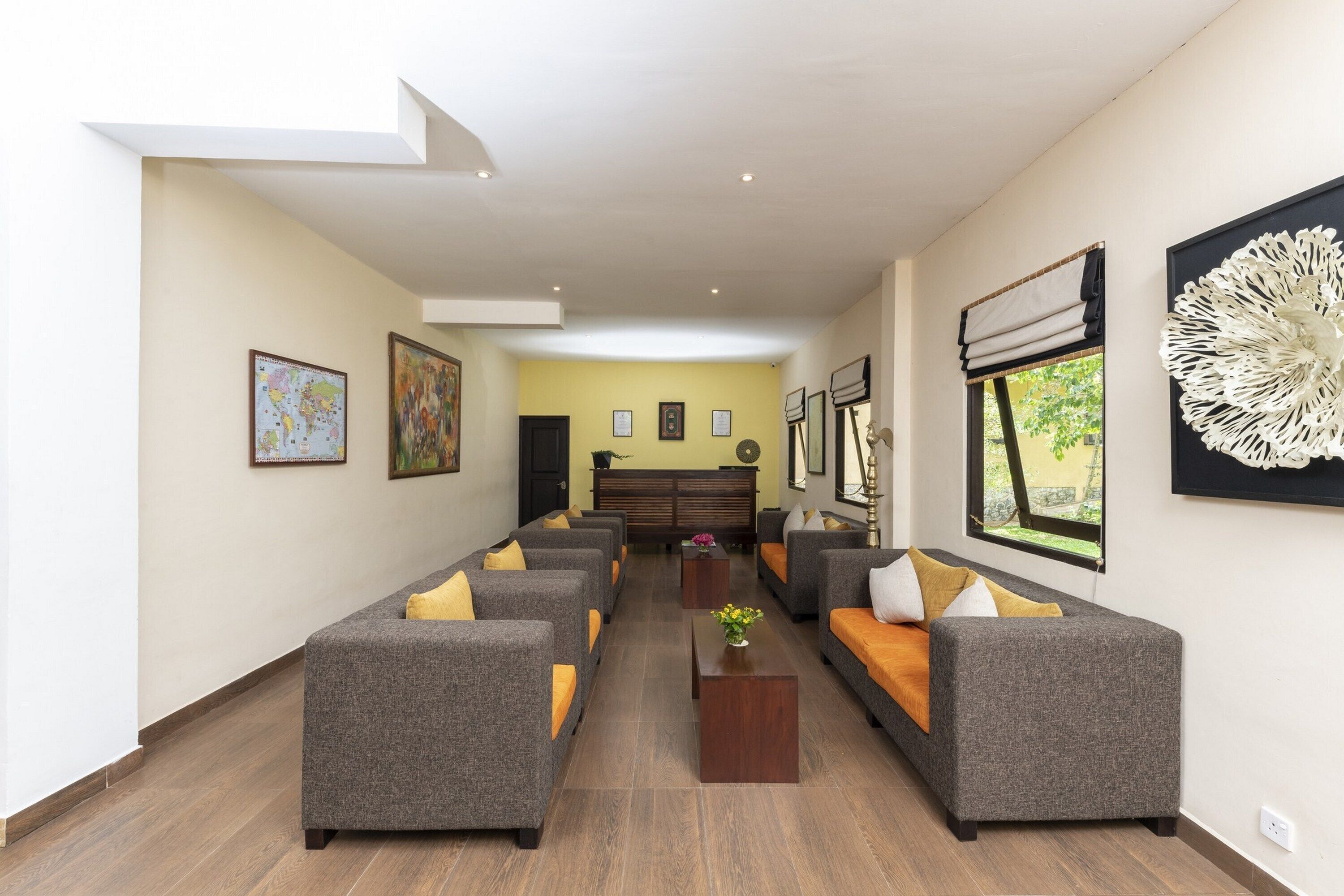 A modern lounge area with sofas and a central coffee table, framed artwork on the walls, and a window with a view.