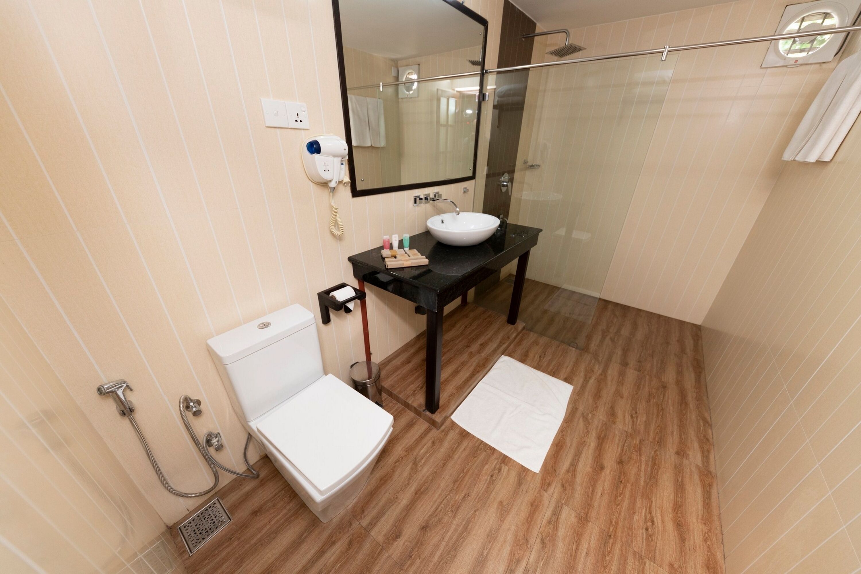 A bathroom with a white sink, a mirror, a toilet, and a shower.