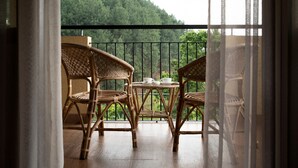 A balcony with wicker chairs and a table, overlooking a forested hillside. - Melheim Kandy Villas (Kandy)